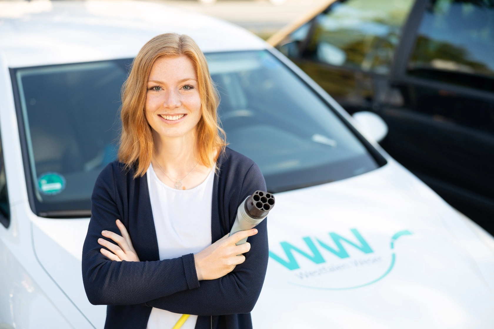 Elektromobilität Privatkunde WW Frau beim Aufladen mit Stecker für Elektroauto Westfalen Weser