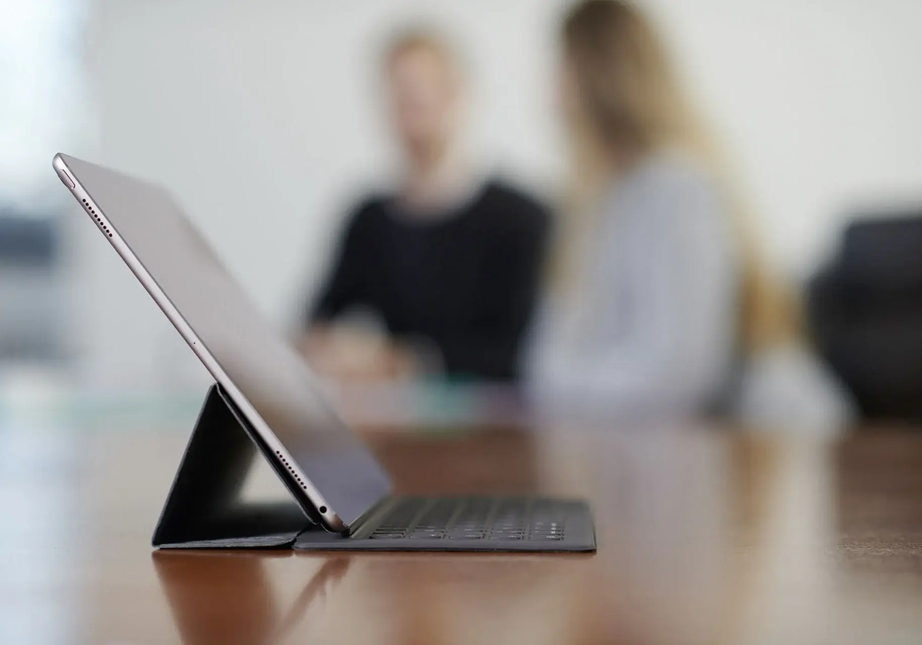 WWN Anmelden Abmelden Tablet auf einem Tisch mit Mitarbeitern unscharf im Hintergrund